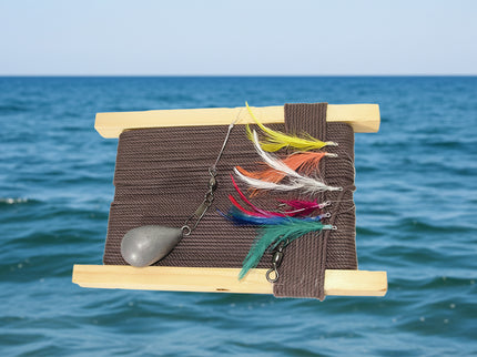 A wooden handline fishing tackle with brown braided twine, multicolored mackerel feathers, and a weight attached.